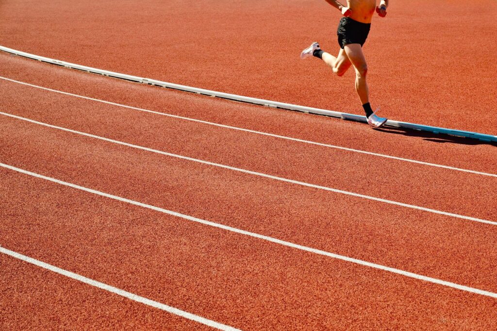Coureur vu de profil en pleine foulée sur une piste d'athlétisme extérieure