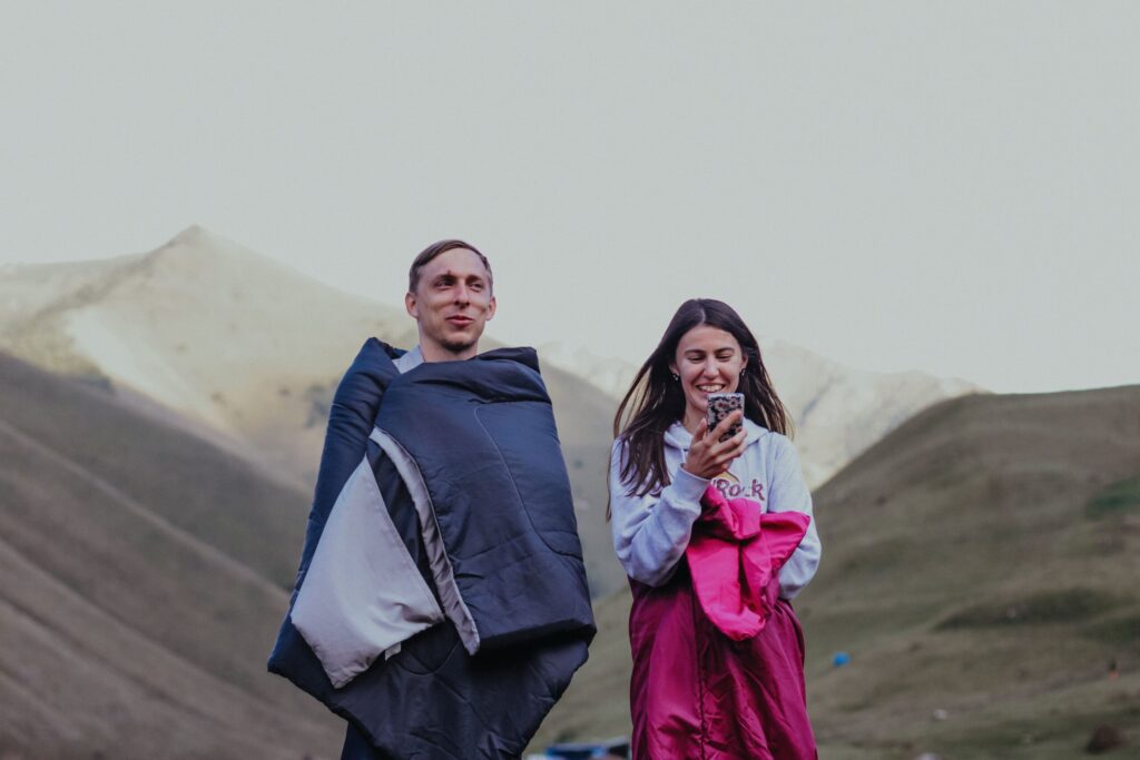 Deux randonneurs installés dans leurs sacs de couchage en duvet, au bivouac en montagne.
