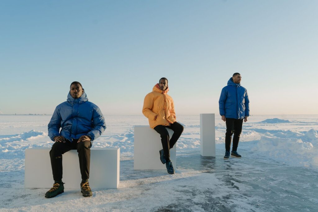 Trois randonneurs en doudoune synthétique dans un paysage enneigé sous un ciel bleu