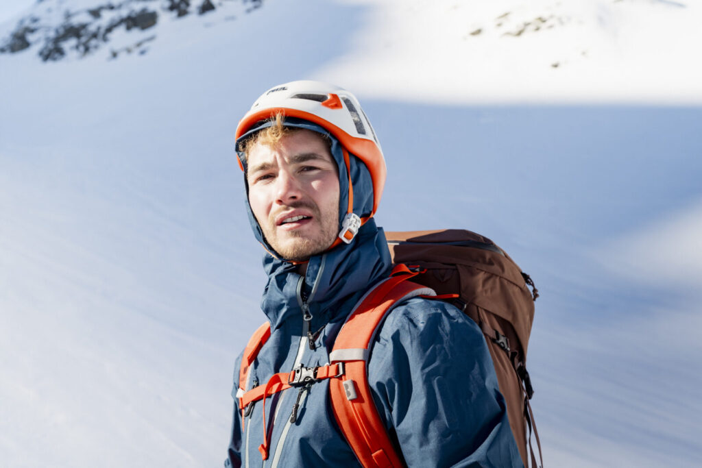 Vallon enneigé dominé par des arêtes rocheuses, un randonneur isolé au fond du vallon
